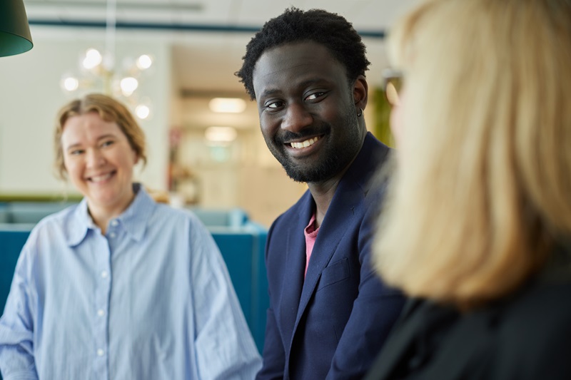 Tre glada personer i kontorslandskap